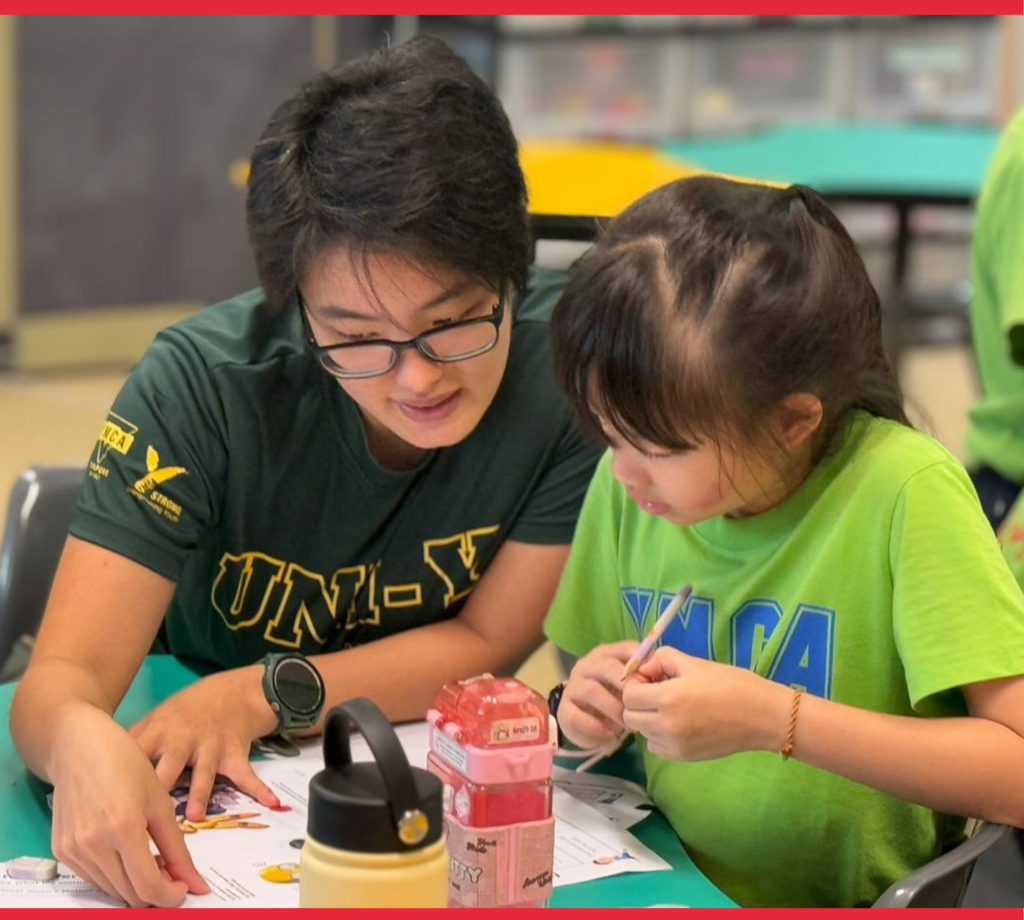 YMCA volunteer and a child doing craft activity